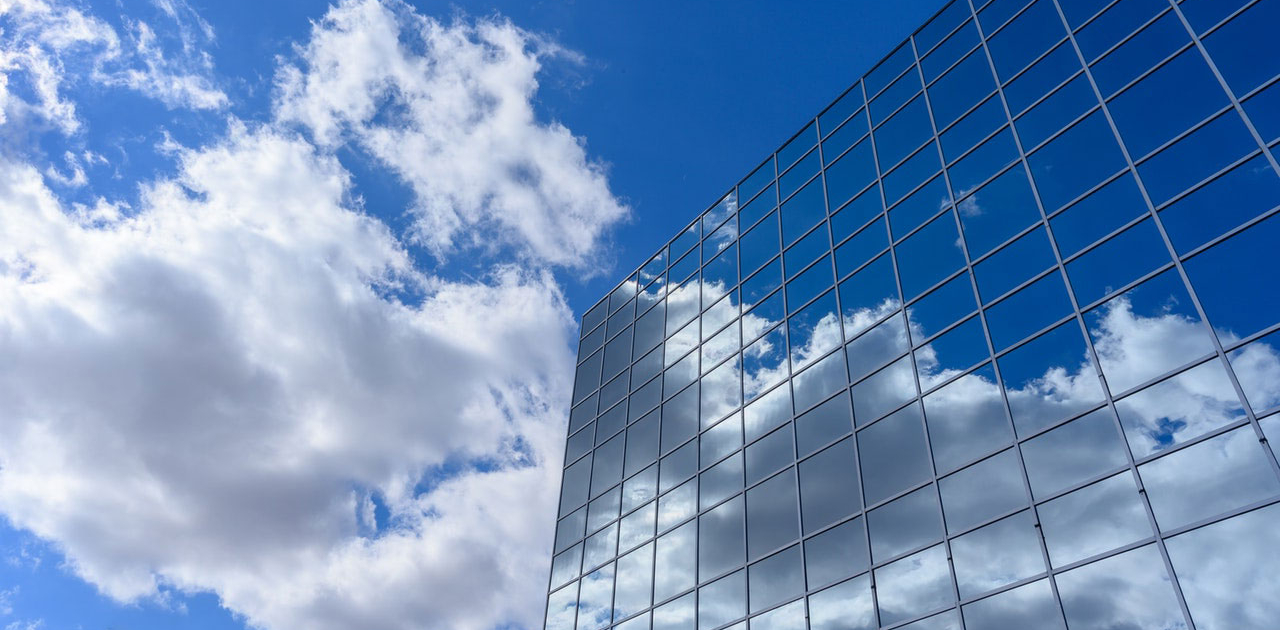 glass office building reflecting clouds